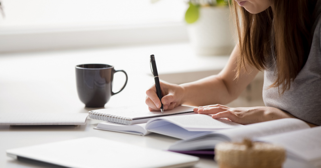 Lady hand-writing on a spiral notepad