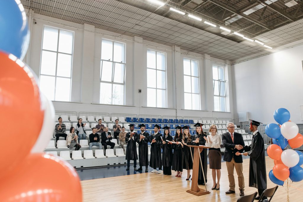 Teachers and staff stand at a podium during a high school graduation