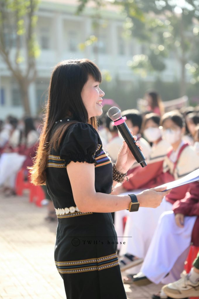 a female stands outside, in front of a crowd and presents