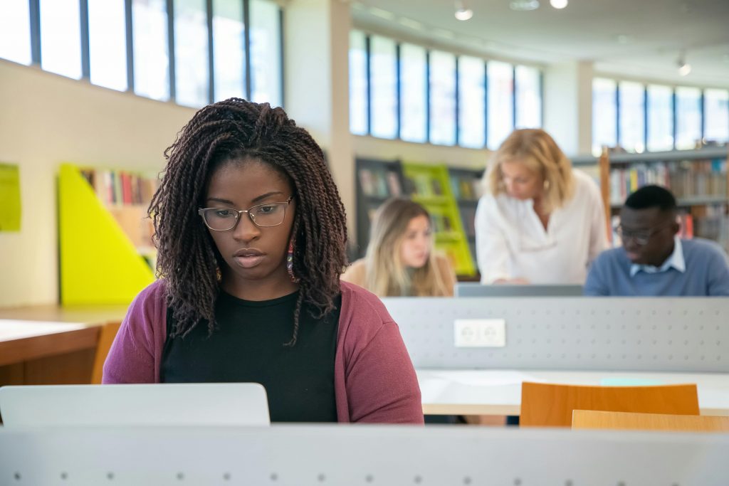 student uses computer in library to write their essay online